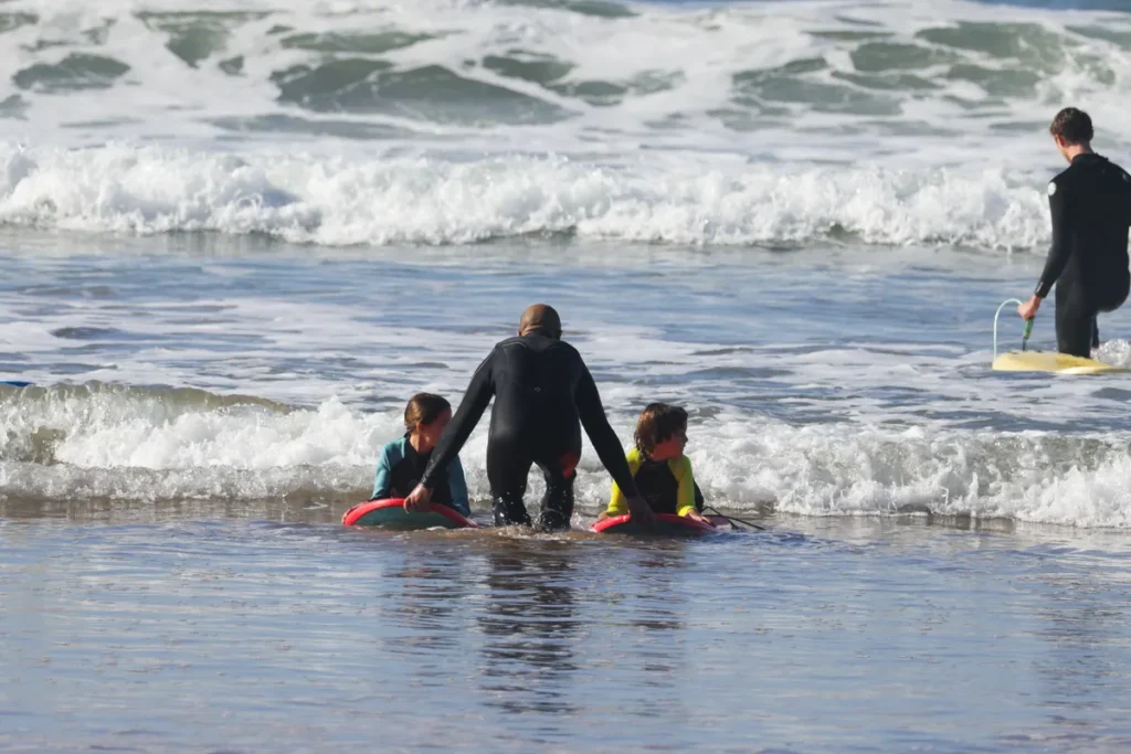 Surflehrer hilft Anfängern im Weißwasser