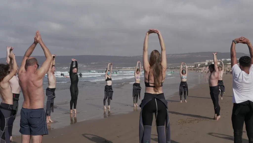Gruppe dehnt sich am Strand vor einer Surfstunde